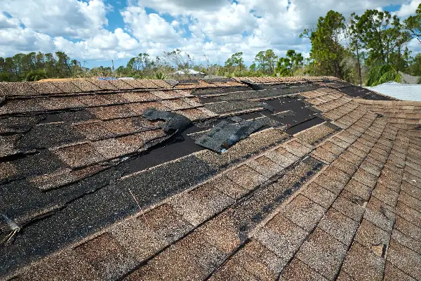 Damaged house roof with missing shingles after storm