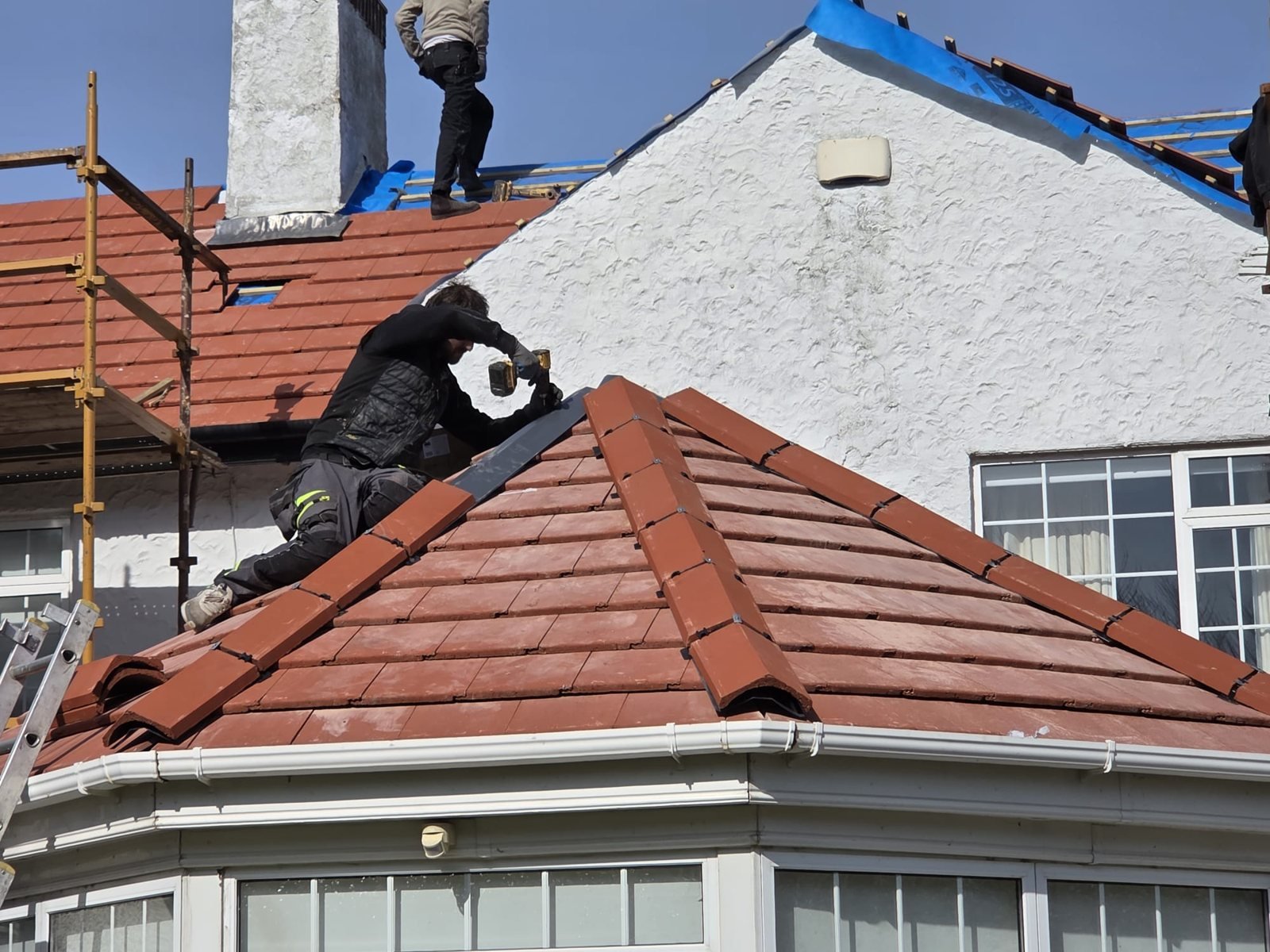 Skyguard roofer fitting ridge tiles on a new tile roof